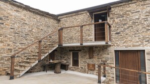 Un edificio de piedra con una escalera de madera que lleva a un balcón.