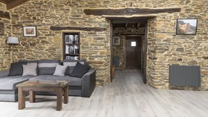 Una habitación con paredes de piedra, un sofá, una mesa de centro y una estantería.