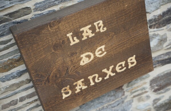 Un letrero de madera con texto grabado sobre un fondo de pared de piedra.
