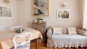 Une pièce comprenant une table à manger, un canapé, une cheminée et des œuvres d’art encadrées accrochées aux murs.