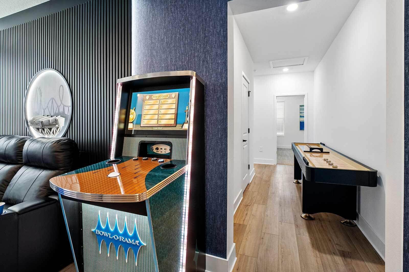 A room with a foosball table, a pool table, and a foosball table with a scoreboard.