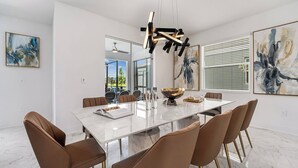 A modern dining room with a marble table, brown leather chairs, and abstract art on the walls.