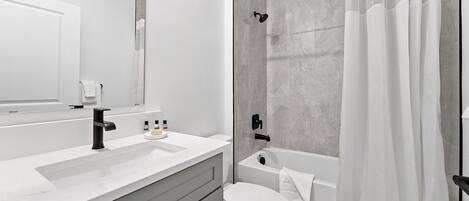 Un baño moderno con lavamanos blanco, inodoro, bañera y ducha.