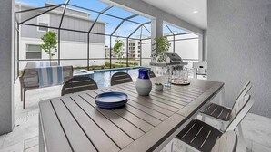 Ein Essbereich im Freien mit Blick auf einen Pool, einem Grill und Sitzgelegenheiten.