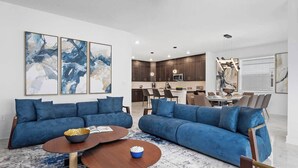 Ein modernes Wohnzimmer mit zwei blauen Sofas, einem Holztisch und abstrakter Kunst an der Wand.