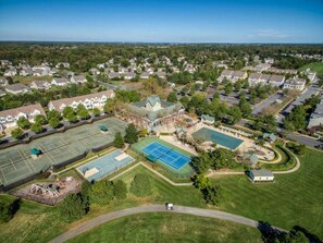 An aerial view of a residential area with multiple houses, a tennis court, and a swimming pool. - Bear Trap Dunes Resort Bethany Beach 4BR, 3.5 Bath (Ocean View)
