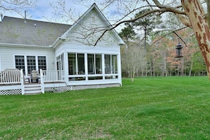 A white house with a covered porch, large windows, and a lawn.