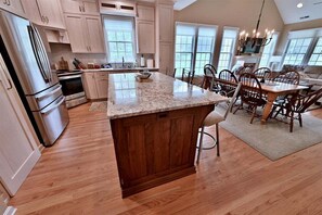 A kitchen with wooden cabinets, a granite countertop island, and a dining area with a table and chairs.