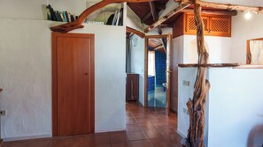 Un couloir avec une porte en bois, une poutre en bois rustique et un sol carrelé.