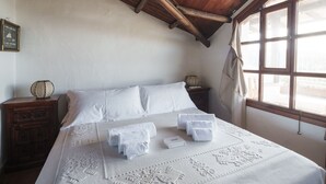 A neatly made bed with white linens and a decorative white bedspread. There are two bedside tables with decorative items on them. - Panoramic Attic with Pool | Near Costa Smeralda (Olbia)