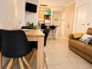 A modern living space with a dining area, a sofa, and a kitchen in the background. - PLATAN ApartHotel - Family sized condo with pool, 2 min from the beach! (Salou)