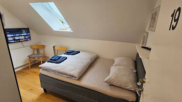 A bedroom with a bed, a desk, and a TV mounted on the wall.