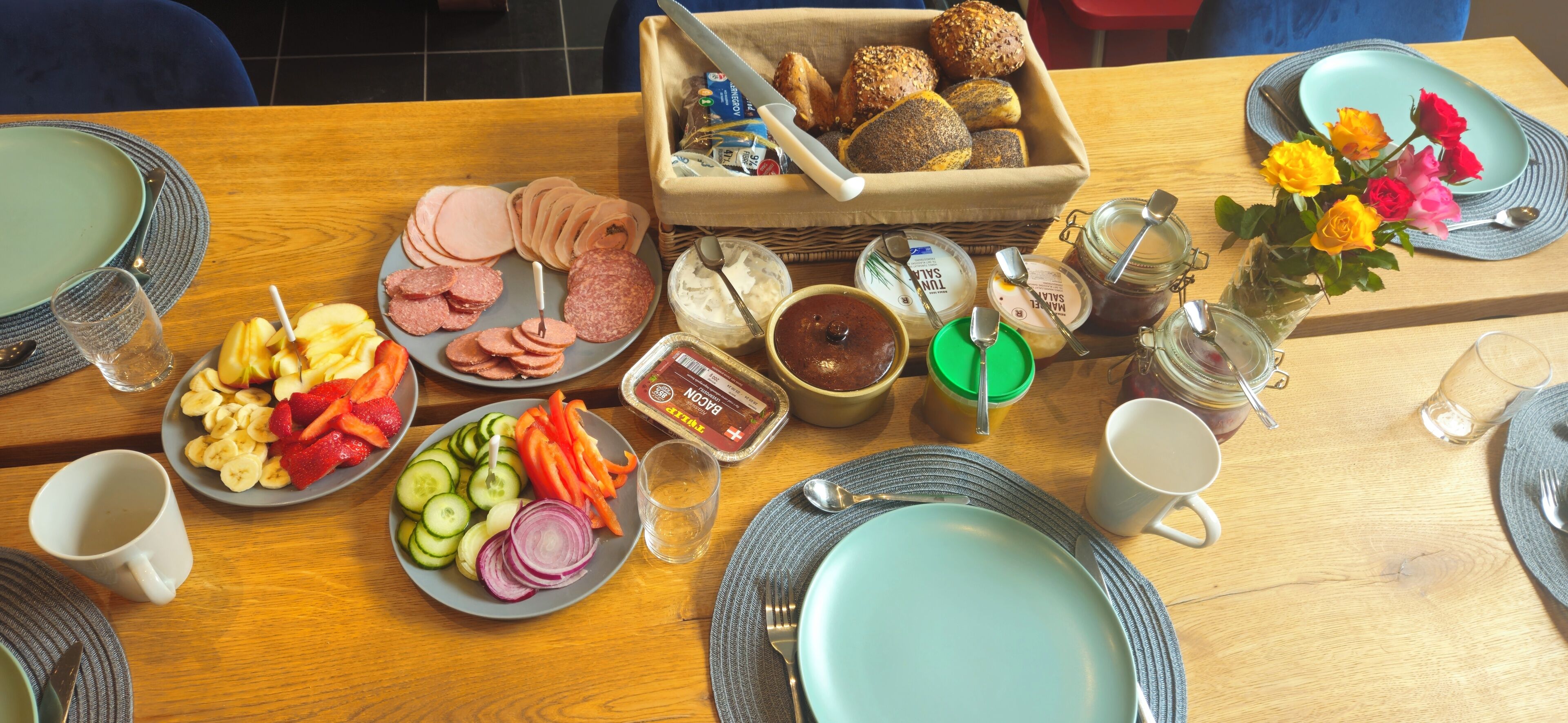 A breakfast setting with plates of food, a bread basket, and condiments.