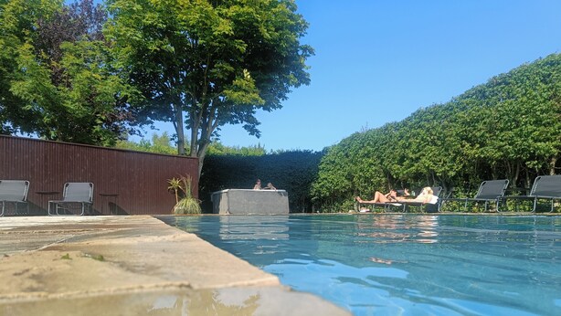 A swimming pool with lounge chairs and a wooden fence. - Olsson B&B (Randers)