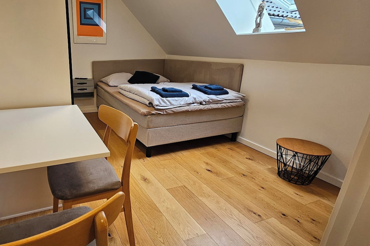 A small, compact room with a bed, a desk, and a chair.
