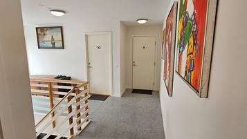 A hallway with a staircase, doors numbered 10 and 11, a painting on the wall, and a colorful artwork.