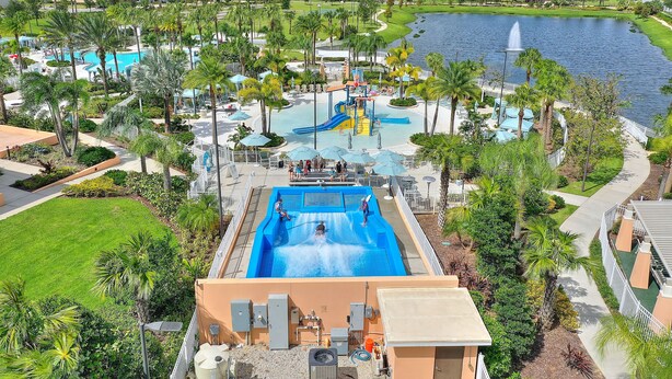 A water park with a large pool, palm trees, and a lake.