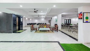 A spacious hotel lobby with a seating area, a dining setup, and a reception desk. - Treebo Saffron (Lucknow)