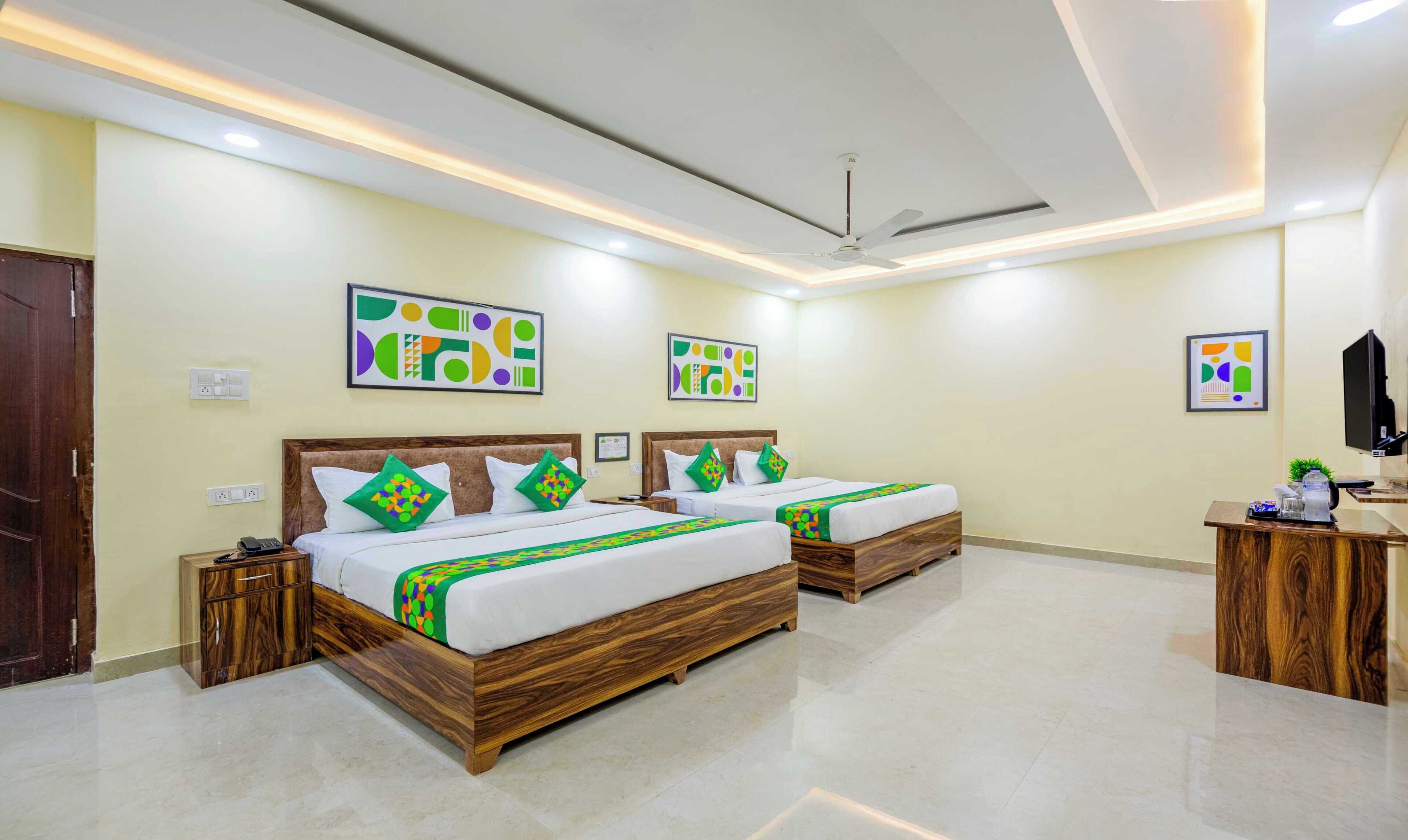 A hotel room with two beds, a desk, and a ceiling fan.