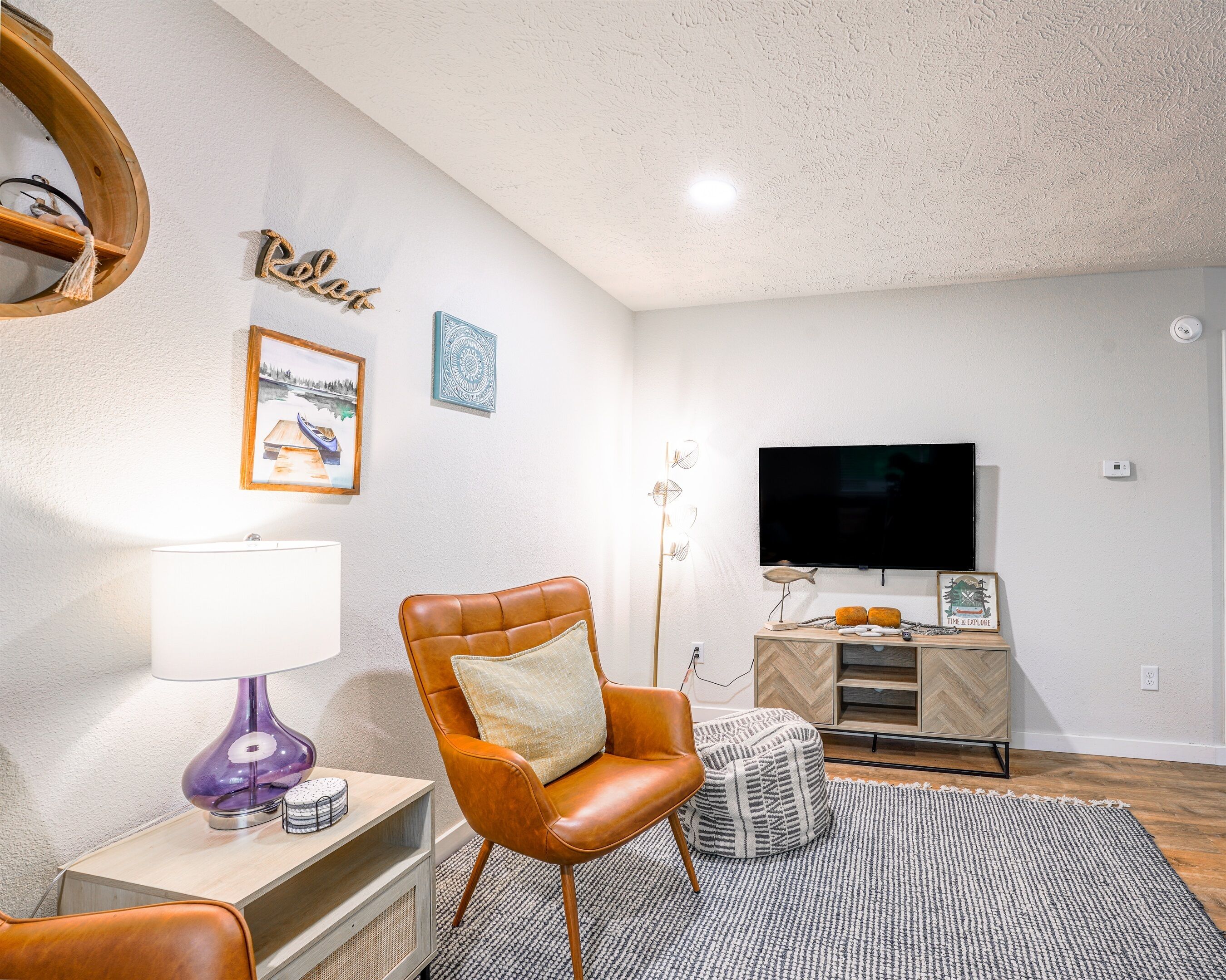A modern living room with a leather armchair, a flat-screen TV, and a wooden cabinet.