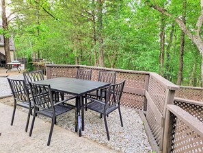 Une terrasse extérieure avec une table et des chaises, entourée d’une clôture en bois et d’arbres.