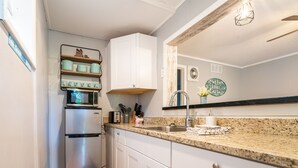 A compact kitchen with white cabinets, a stainless steel refrigerator, a microwave, and a sink with a faucet. - Tribesman Resort #10 - Renovated Condo, Mins to Silver Dollar, Great Location! (Branson)