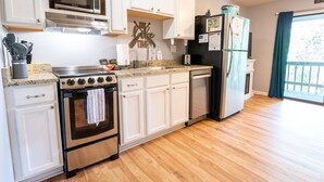 Una cocina moderna con armarios blancos, electrodomésticos de acero inoxidable y piso de madera.
