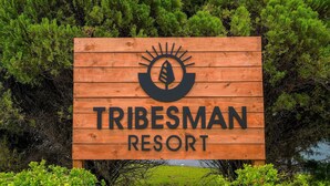 Un letrero de madera para Tribesman Resort con un logotipo encima del texto.