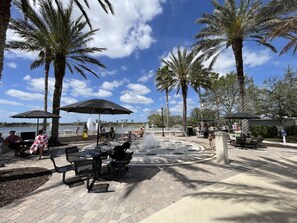 An outdoor patio with tables and chairs, umbrellas, and a water fountain.