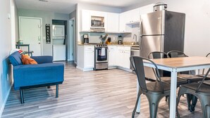 Een moderne keuken met witte kasten, roestvrijstalen apparatuur, en een eethoek met een tafel en stoelen.