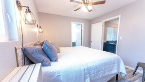 Een slaapkamer met een bed, een plafondventilator en twee wandlampen.