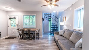 A modern kitchen with a dining table and chairs, a built-in oven, and a ceiling fan. - Tribesman Resort #23 - Renovated Cabin, Minutes to Silver Dollar, Great Location (Branson)