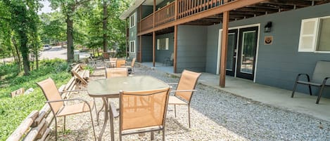 An outdoor patio with a table and chairs, surrounded by gravel and greenery.