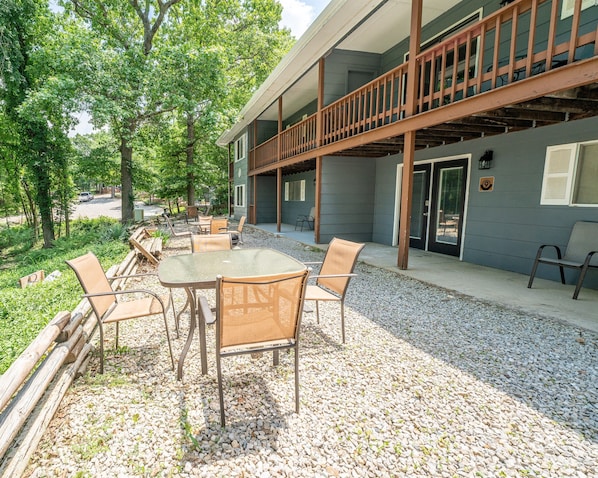 An outdoor patio with a table and chairs, surrounded by gravel and greenery.