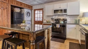 A kitchen with a central island, a washing machine, a stove, and a microwave. - *Romantic 3BD w/ HOT TUB! Nestled in the WOODS!* (Pigeon Forge)