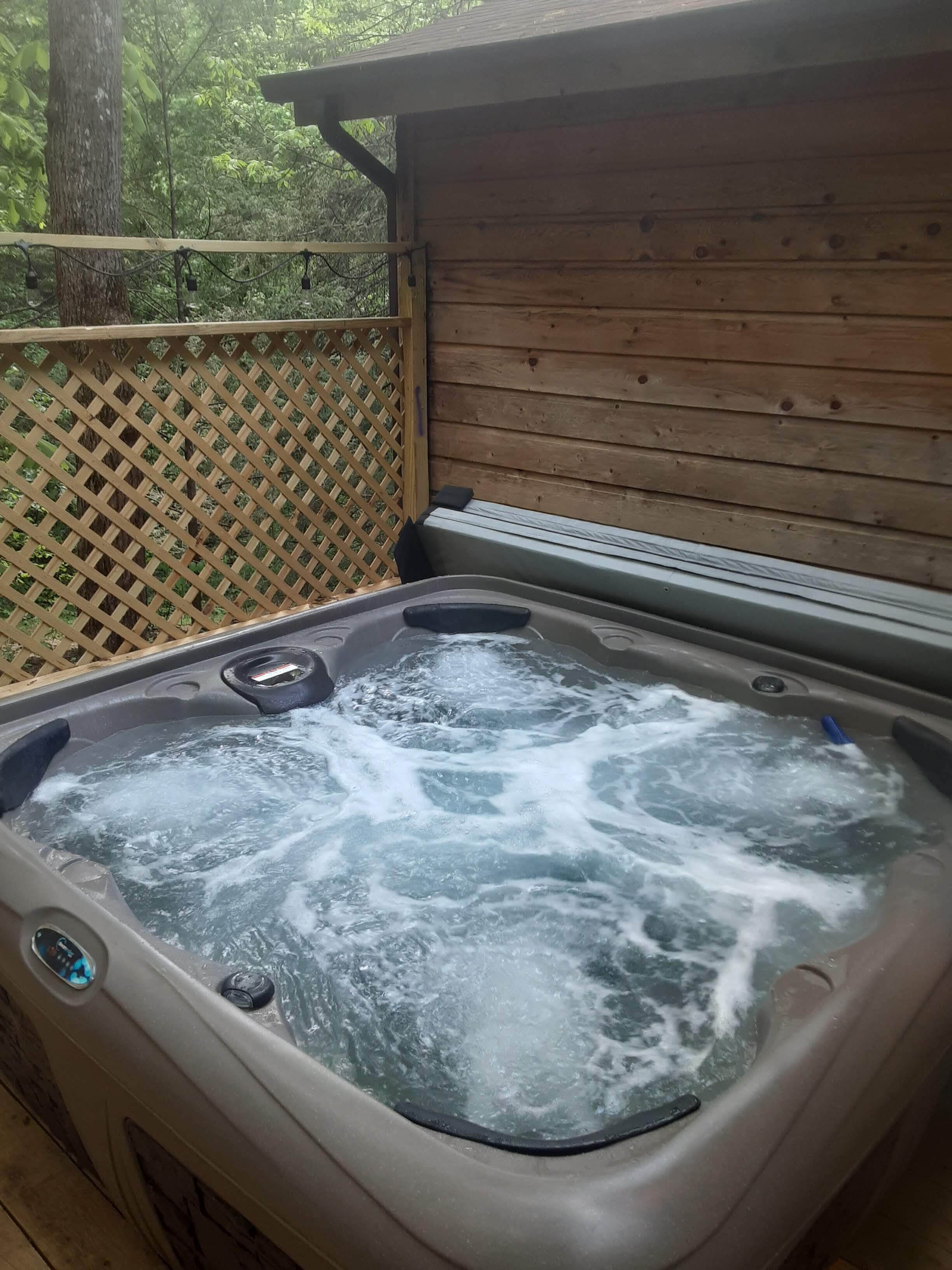 A hot tub with a wooden deck and a wooden fence in the background.