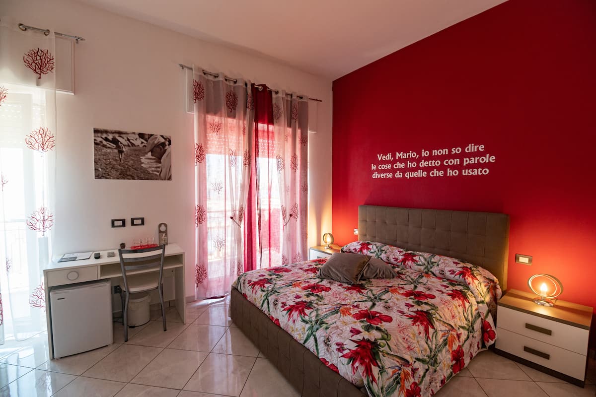 A bedroom with a bed, a desk, and a chair.