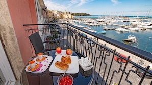 Un balcone con un tavolo apparecchiato per la colazione, con vista su una marina piena di barche.