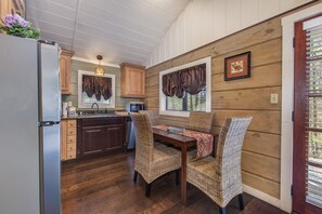Eine Küche mit Holzschränken, einem Kühlschrank, einer Mikrowelle und einem Esstisch mit Korbstühlen.