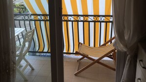 A balcony with a striped awning, a folding chair, and a view of the outside. - Casa Greta 5 minutes walk from the beautiful beaches and cycle path.
Balcony (Arma di Taggia)