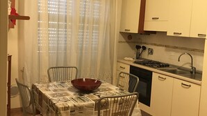 A small kitchen with white cabinets, a stove, and a sink. There is a dining table with chairs and a red bowl on it. - Casa Greta 5 minutes walk from the beautiful beaches and cycle path.
Balcony (Arma di Taggia)