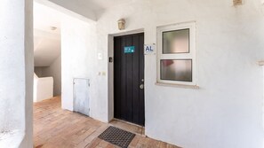 A hallway with a black door, a small window, and a sign indicating 'AL' (Apartamento Local).