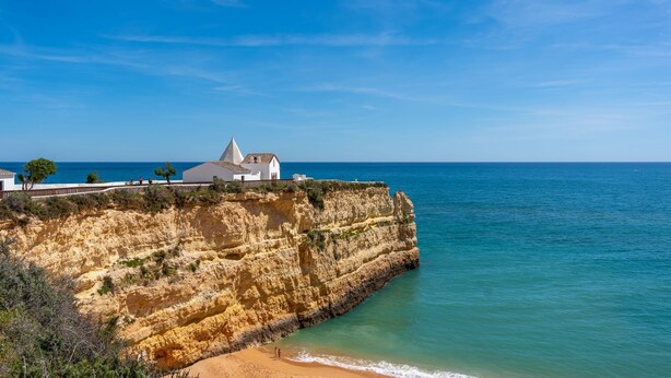 Un bâtiment situé sur la côte, doté d’une façade blanche et d’un toit conique, et qui se trouve sur une falaise surplombant la mer.