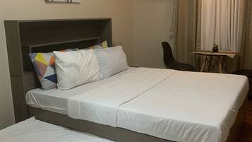A double bed with white bedding, a headboard, and a colorful pillow arrangement.
