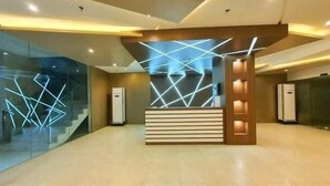 A modern reception desk with geometric light patterns, a glass wall, and a tiled floor. - Cebu Rooms- Sunvida Tower (Cebu City)