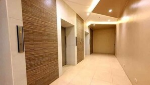 A hallway with a wooden accent wall, a door, and a light-colored tiled floor. - Cebu Rooms- Sunvida Tower (Cebu City)