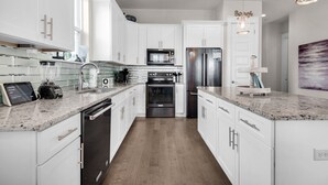 Una cocina moderna con armarios blancos, electrodomésticos de acero inoxidable y encimeras de granito.