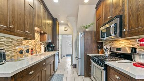 A modern kitchen with wooden cabinets, a stainless steel refrigerator, a microwave, and a gas stove. - MINNeSTAY* Lyndale Pleasant Getaway (Minneapolis)