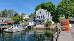 A waterfront property with a dock, a boat, and a house with a balcony.