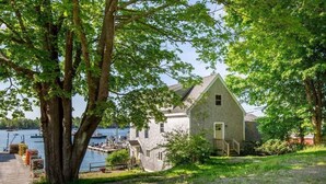 A house with a dock by a lake, surrounded by trees.